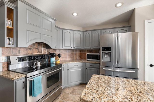 kitchen with backsplash, gray cabinetry, light stone counters, recessed lighting, and stainless steel appliances