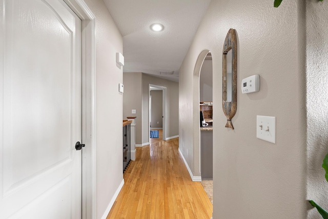 hall with visible vents, light wood-style flooring, and baseboards