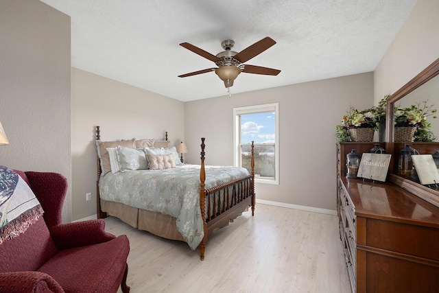 bedroom featuring light wood-style flooring, a textured ceiling, a ceiling fan, and baseboards