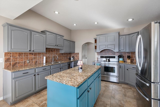 kitchen featuring gray cabinetry, custom exhaust hood, arched walkways, stainless steel appliances, and a sink