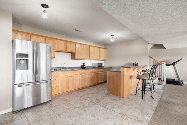 kitchen with visible vents, a breakfast bar, a sink, stainless steel appliances, and dark countertops