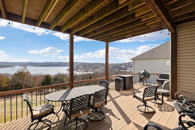 deck with outdoor dining area, a water view, and area for grilling