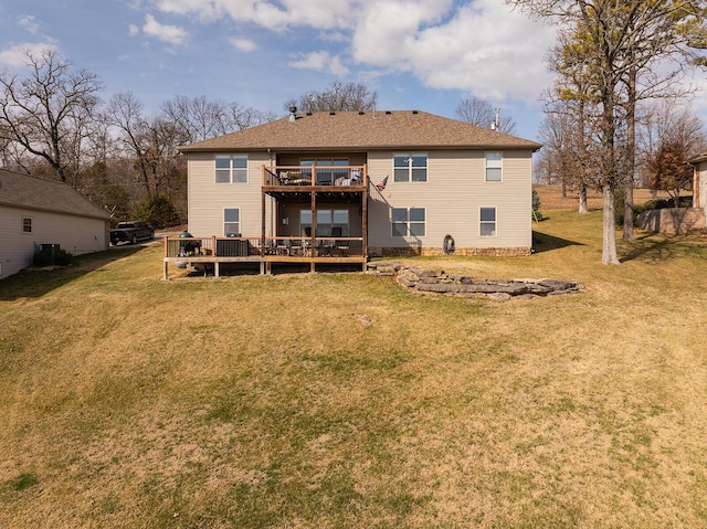 rear view of house with a deck, a balcony, and a lawn