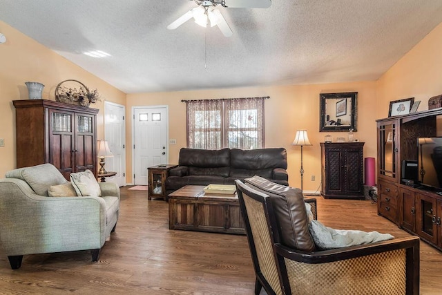 living area featuring a textured ceiling, vaulted ceiling, wood finished floors, and ceiling fan