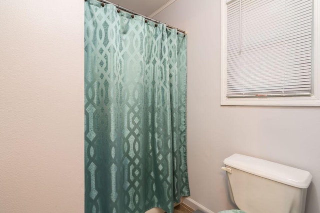 full bathroom featuring toilet, a shower with shower curtain, baseboards, and ornamental molding