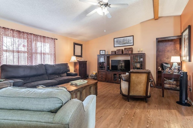 living area with wood finished floors, vaulted ceiling with beams, a ceiling fan, and a textured ceiling