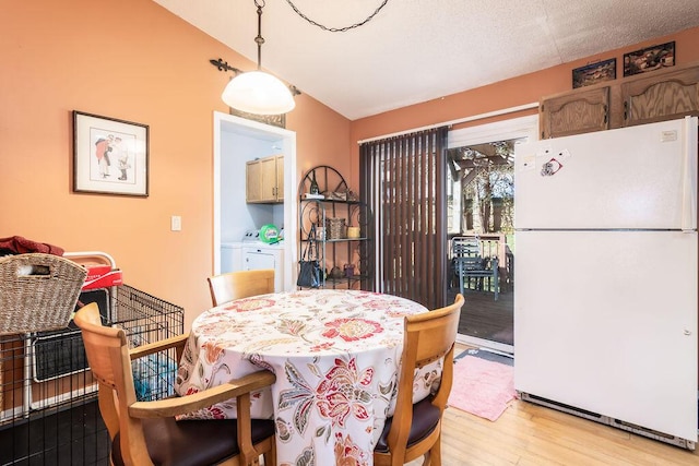 dining area with separate washer and dryer, light wood-style floors, and lofted ceiling