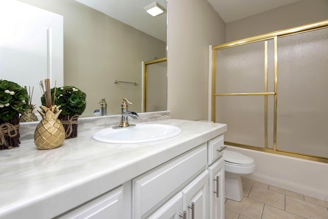 bathroom with tile patterned floors, enclosed tub / shower combo, toilet, and vanity