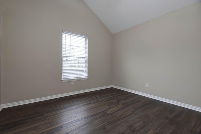 empty room featuring dark wood finished floors, visible vents, baseboards, and lofted ceiling