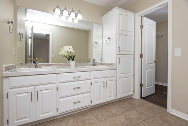 full bath featuring a sink, baseboards, double vanity, and tile patterned flooring