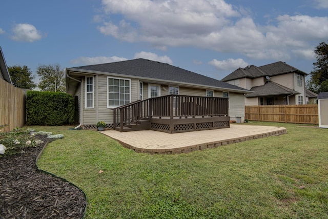 back of house featuring a shingled roof, a wooden deck, a fenced backyard, a yard, and a patio