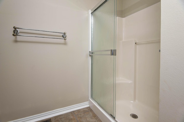 bathroom with tile patterned flooring, baseboards, and a stall shower