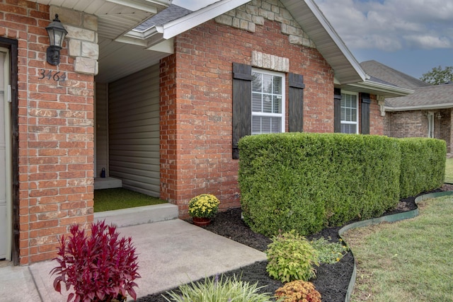 view of side of home featuring brick siding and a shingled roof