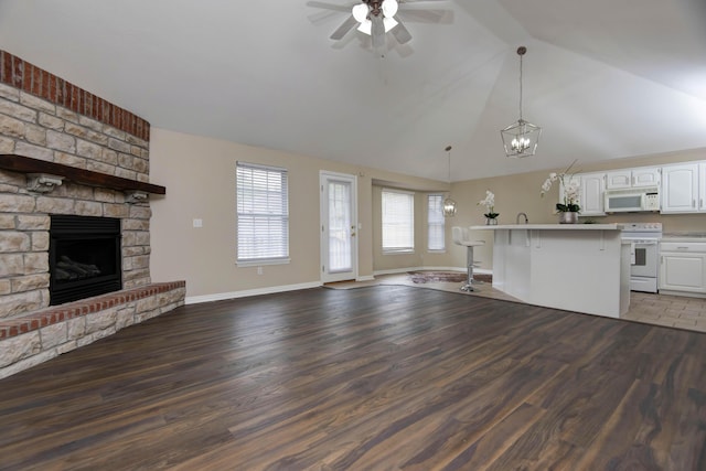 kitchen with a fireplace, white appliances, wood finished floors, and open floor plan