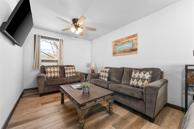 living room with baseboards, light wood-type flooring, and ceiling fan