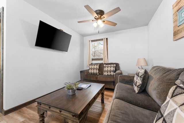 living room featuring light wood-style flooring, baseboards, and ceiling fan