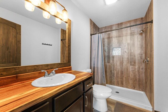 bathroom with tiled shower, toilet, and vanity