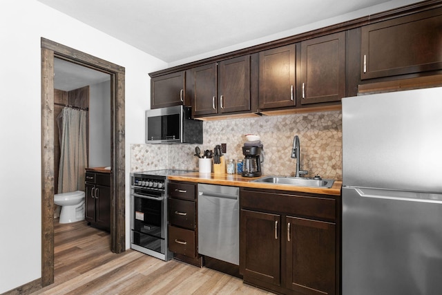 kitchen featuring a sink, decorative backsplash, dark brown cabinetry, and appliances with stainless steel finishes