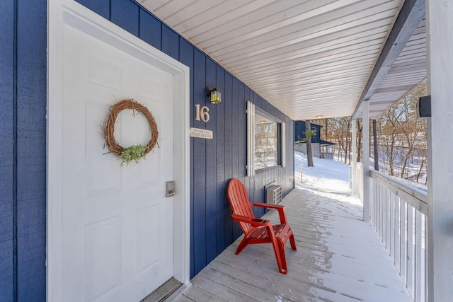 snow covered property entrance featuring covered porch