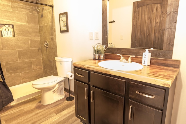 full bath with vanity, toilet, wood finished floors, and tiled shower