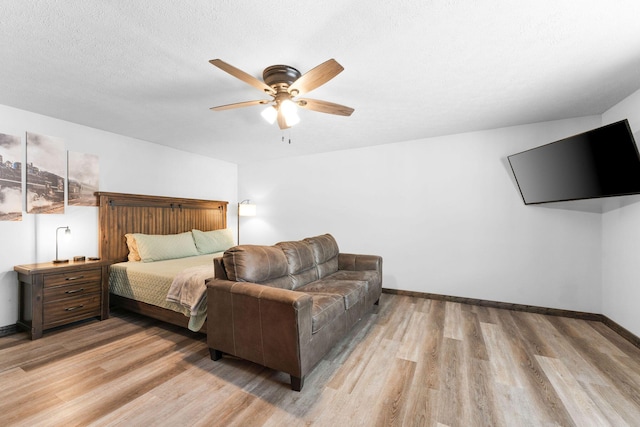 bedroom featuring light wood-type flooring, baseboards, a textured ceiling, and ceiling fan