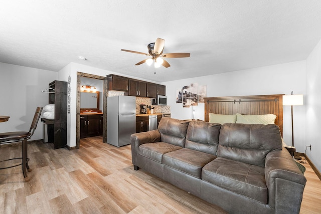 living room featuring baseboards, ceiling fan, and light wood finished floors