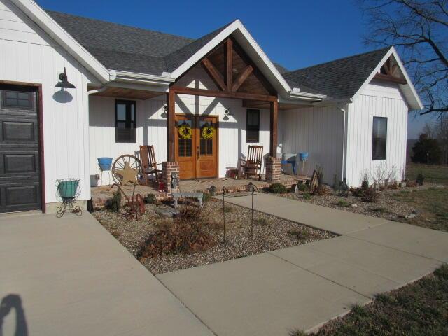 property entrance with french doors, a shingled roof, and a garage