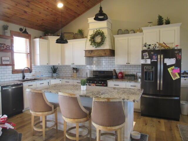 kitchen featuring black fridge, custom range hood, stainless steel dishwasher, gas stove, and wood ceiling