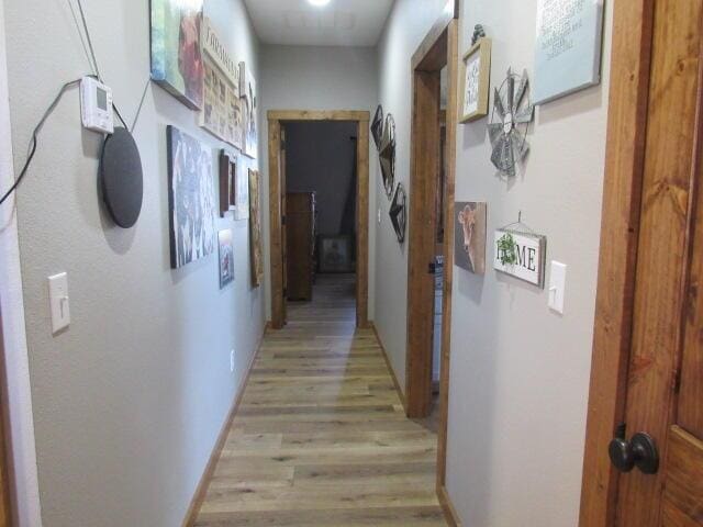 corridor featuring light wood-style flooring and baseboards