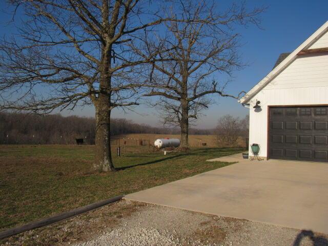 view of yard featuring concrete driveway and a garage