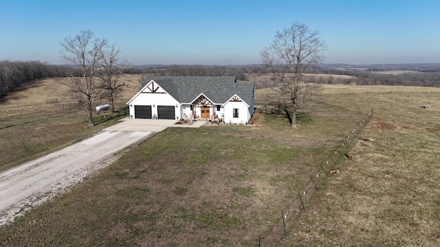 view of front of property with a garage, driveway, a rural view, and a front lawn