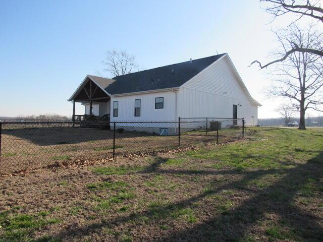 rear view of house with a yard and fence