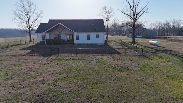 back of house with a rural view, fence private yard, and a lawn