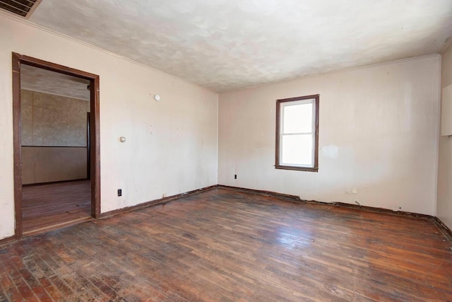 spare room featuring visible vents, crown molding, baseboards, and wood finished floors