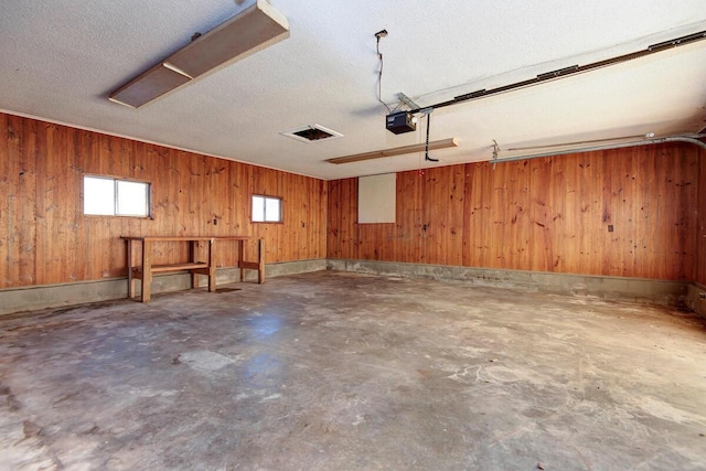 garage featuring a garage door opener and wood walls