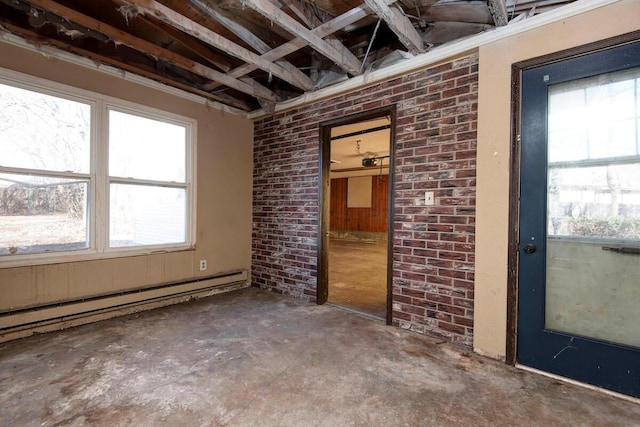 empty room with a baseboard heating unit, unfinished concrete floors, and brick wall