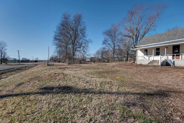 view of yard with covered porch and fence