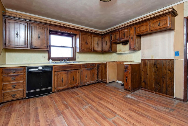 kitchen featuring a sink, black dishwasher, wood finished floors, and light countertops