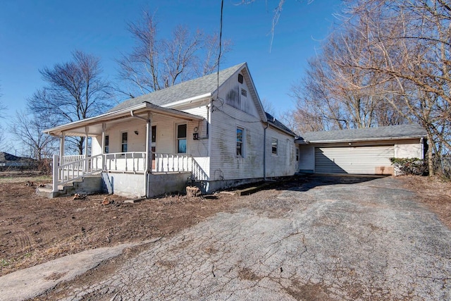 view of front of home featuring a garage, a porch, and driveway