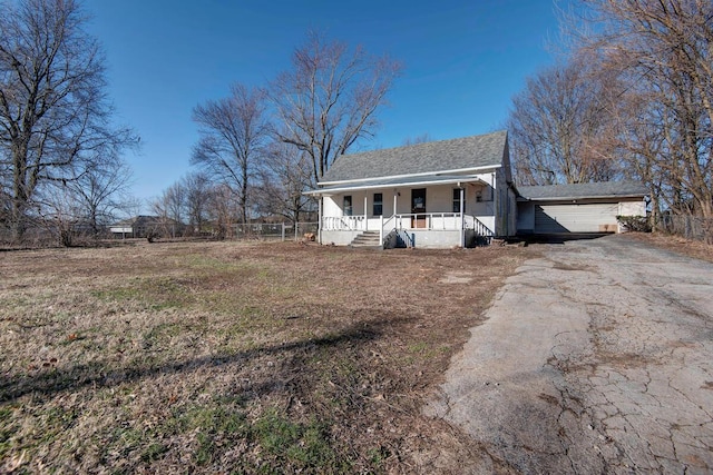 view of front facade featuring aphalt driveway, an attached garage, fence, and covered porch