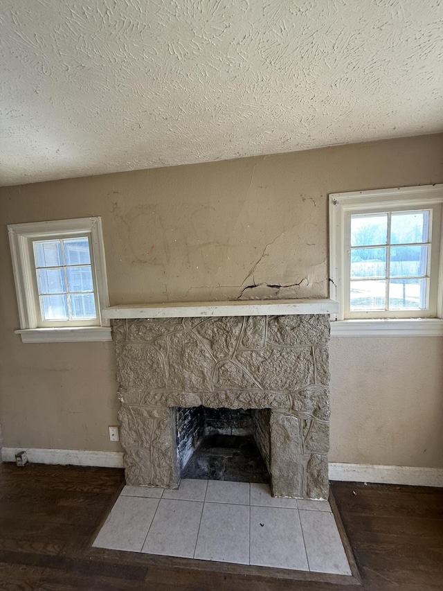 details featuring a fireplace, a textured ceiling, baseboards, and wood finished floors