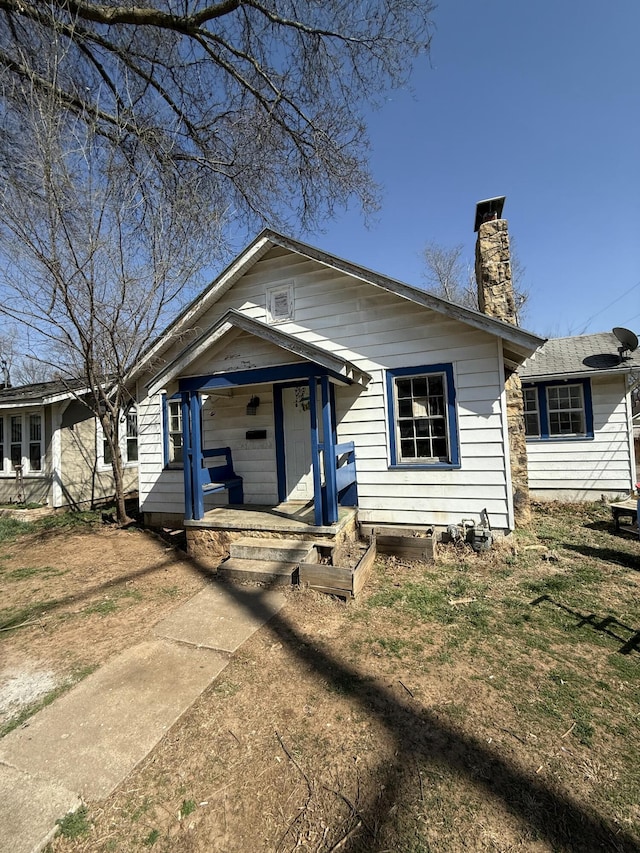 bungalow with covered porch and a chimney