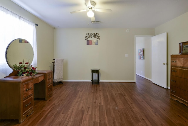 interior space featuring dark wood-type flooring, a ceiling fan, visible vents, and baseboards