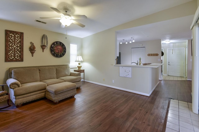 living area featuring a ceiling fan, wood finished floors, visible vents, and baseboards