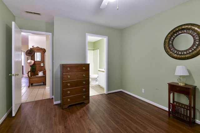 bedroom with wood finished floors, visible vents, baseboards, ceiling fan, and connected bathroom