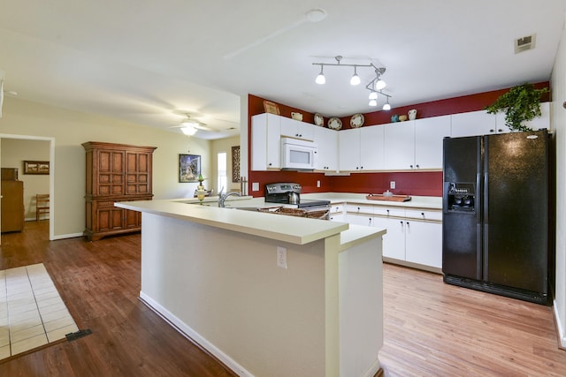 kitchen featuring electric range, visible vents, black fridge, a peninsula, and white microwave