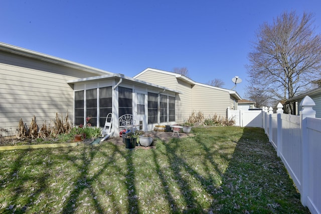 rear view of house featuring a fenced backyard, a yard, and a sunroom