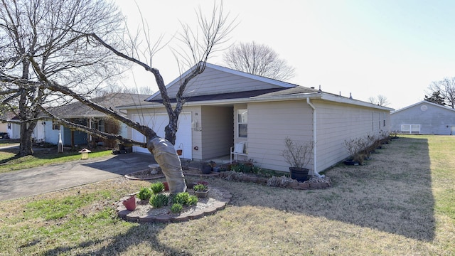 view of front of property featuring aphalt driveway, an attached garage, and a front yard