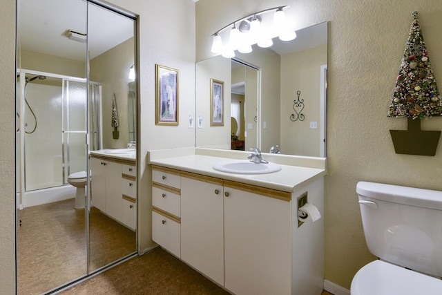 full bath featuring a shower stall, toilet, vanity, and a textured wall