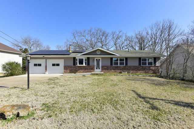 single story home featuring a garage, brick siding, solar panels, and a front lawn